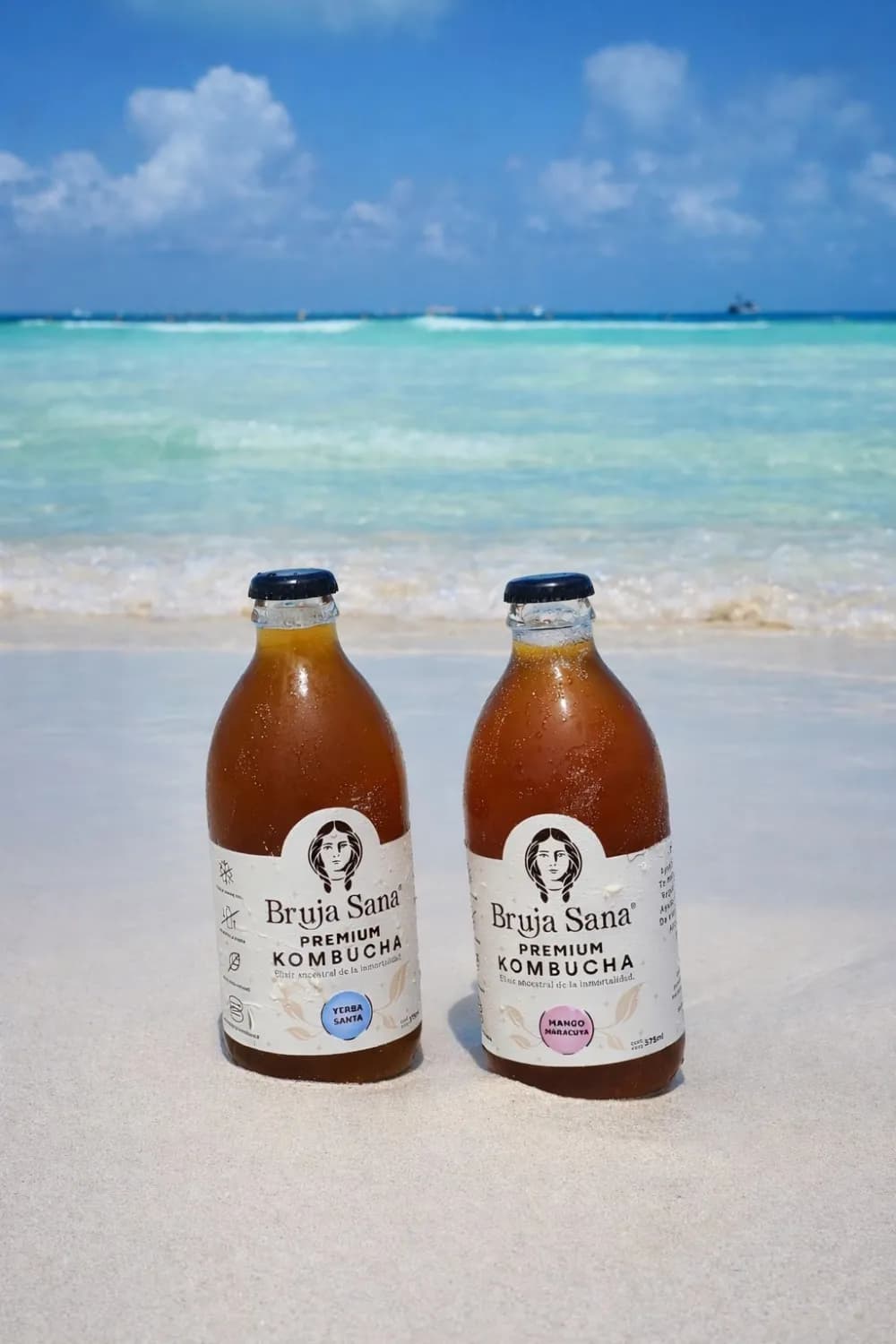Dos botellas de Bruja Sana en una playa de Tulum